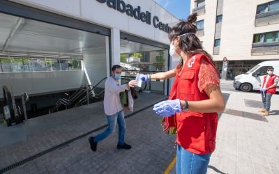 Una voluntària de Creu Roja donant mascaretes a l'entrada de Sabadell Centre | Roger Benet 