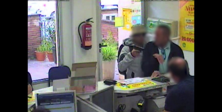 Imatge captada per una càmera de videovigilància en la qual es veu com un home apunta amb una arma un client en una oficina de Correus. ACN 