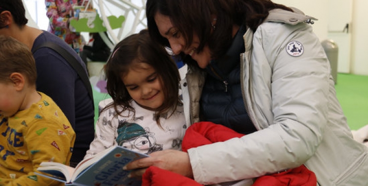 Una mare amb la seva filla llegint un conte | ACN