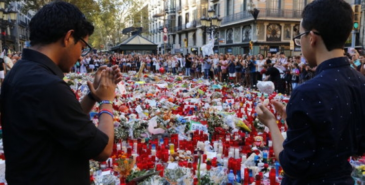 Dos joves aplaudeixen després d'haver fet l'ofrena a les víctimes dels atemptats de Barcelona i Cambrils | ACN
