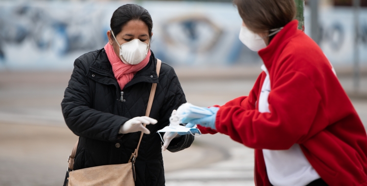 Una voluntària de Creu Roja repartint mascaretes/ Roger Benet