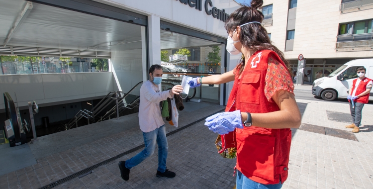 Voluntaris de Creu Roja repartint mascaretes a la sortida dels Ferrocarrils | Roger Benet