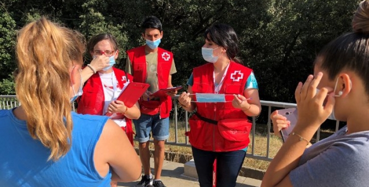 Voluntaris de Creu Roja Sabadell explicant a unes joves com funciona la mascareta | Cedida