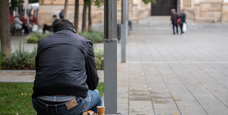 Una persona en un banc de plaça Sant Roc/ Roger Benet