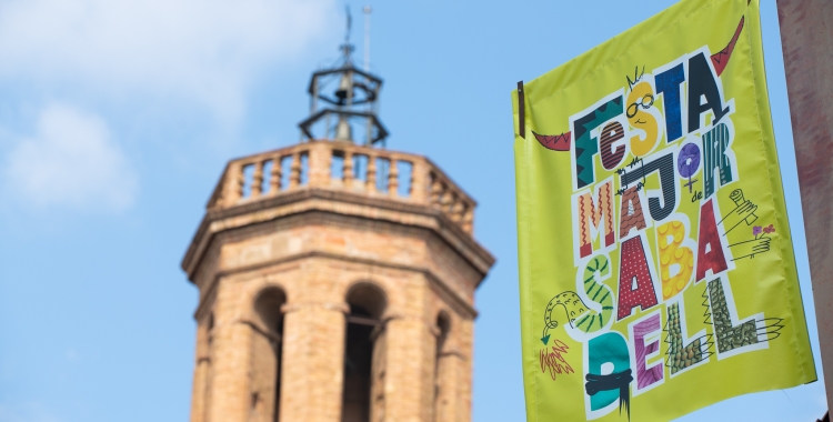 Un cartell de Festa Major, amb el campanar de Sant Fèlix de fons/ Roger Benet