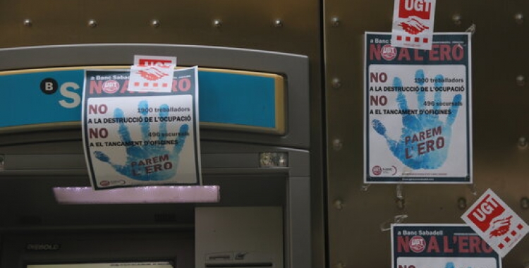 Caixer del Banc Sabadell ple de cartells en contra de l'ERO que ha plantejat l'entitat | ACN