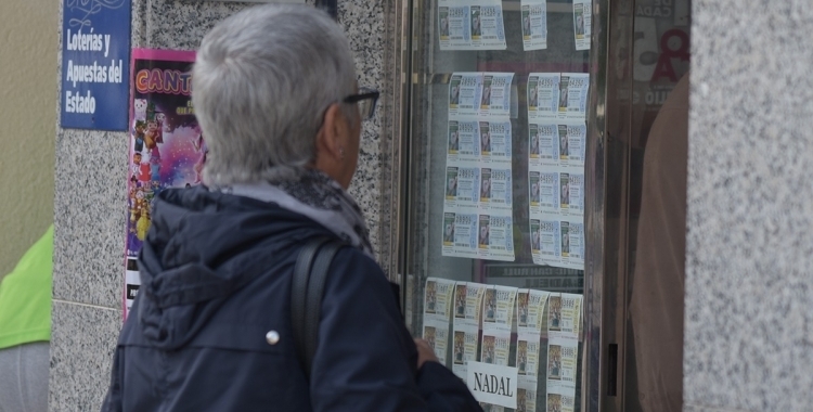 Una dona mira els dècims de loteria d'una administració | Roger Benet