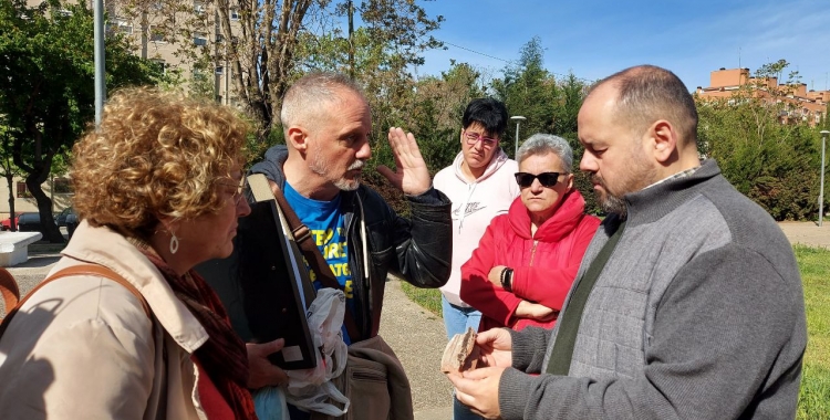 Joan Mena, amb una vigueta dels pisos malmesos a les mans, acompanyat de veïns dels Merinals/ Karen Madrid