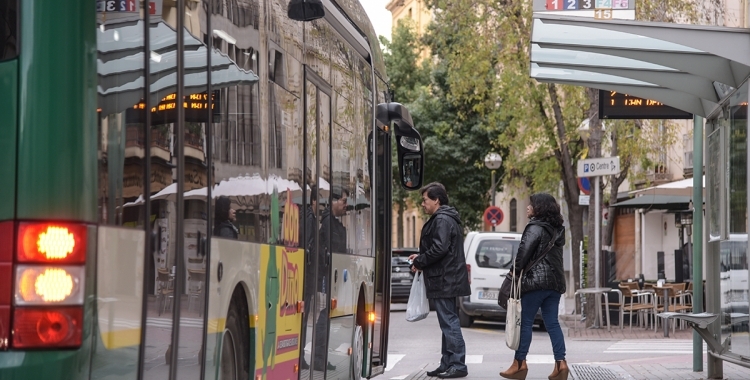 Un parell d'usuaris agafant un autobús de la TUS al carrer Sant Joan | Roger Benet