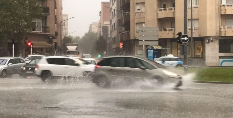 Diversos cotxes circulen a plaça Catalunya amb una forta acumulació d'aigua per la pluja