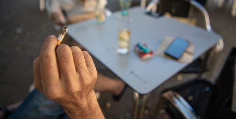 Un client d'una terrassa amb una cigarreta a la mà