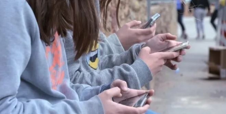 Adolescents utilitzant el mòbil en un centre escolar | cedida