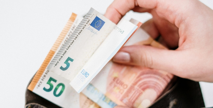 Una persona posant diners en una cartera | Pexels