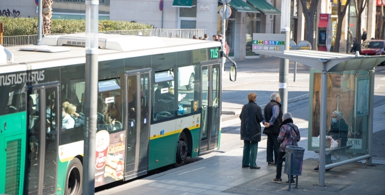 Gent en una parada d'autobús esperant | Arxiu