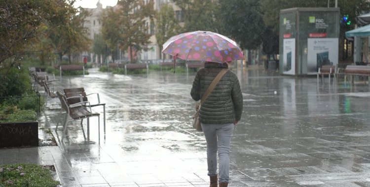 Una dona camina sota el paraigües mentre plou al Passeig | Roger Benet