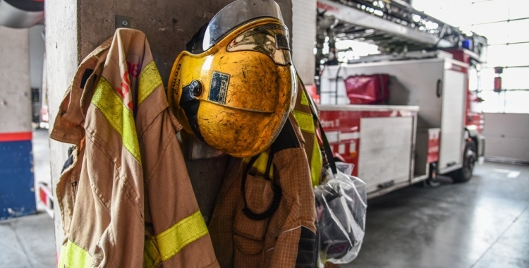 Uniforme de bomber en primer pla i camions al fons | Roger Benet