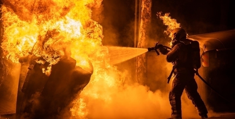 Un bomber treballa en l'extinció de l'incendi d'un contenidor 