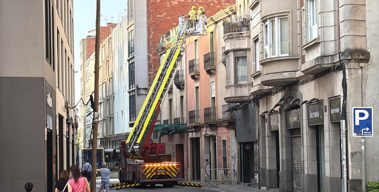 Els Bombers treballen amb l'autoescala en el sanejament de la façana