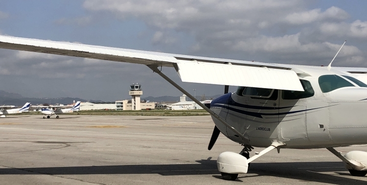 Un avió en primer pla amb la torre de control de l'Aeroport de fons