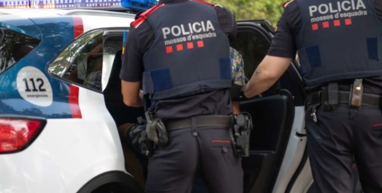 Dos agents dels mossos ficant un detingut al cotxe de Mossos