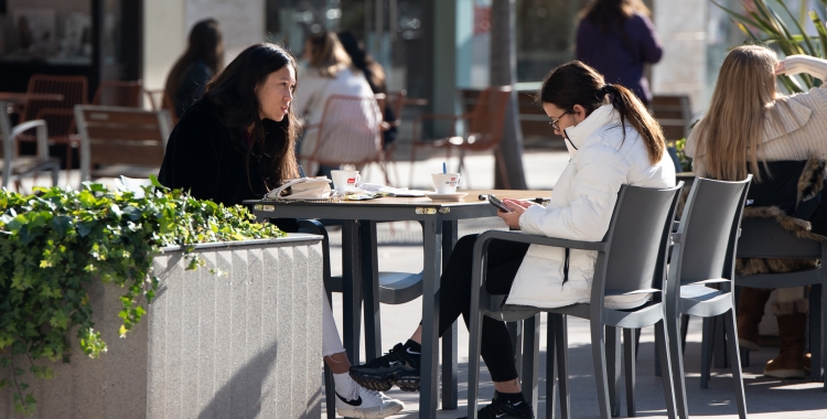 Dues noies prenent un cafè en una terrassa