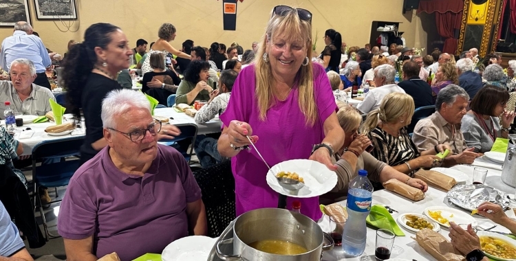 Una dona repartint 'olla con pringá' aquest migdia | Núria García