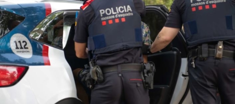 Dos agents dels mossos ficant un detingut al cotxe de Mossos
