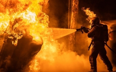Un bomber intenta apagar un foc desenvolupat en un contenidor