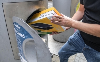 Una persona introdueix una capsa de cartró en un contenidor de pneumàtica