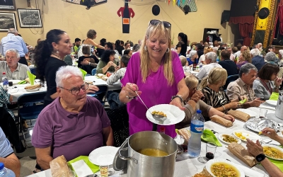 Una dona repartint 'olla con pringá' aquest migdia | Núria García