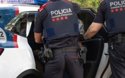 Dos agents dels mossos ficant un detingut al cotxe de Mossos
