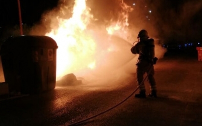 Un bomber apagant l'incendi en un contenidor