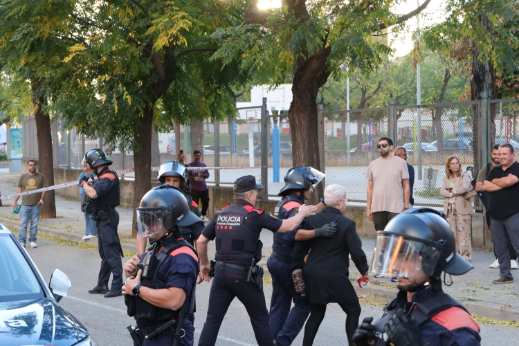 Els Mossos retenint la simpatitzant de VOX després d'intentar llençar una llauna a l'altra banda de la vorera