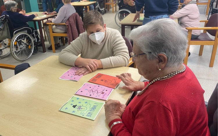 Un dels nens del Consell d'Infants compartint una postal amb una usuària de la residència
